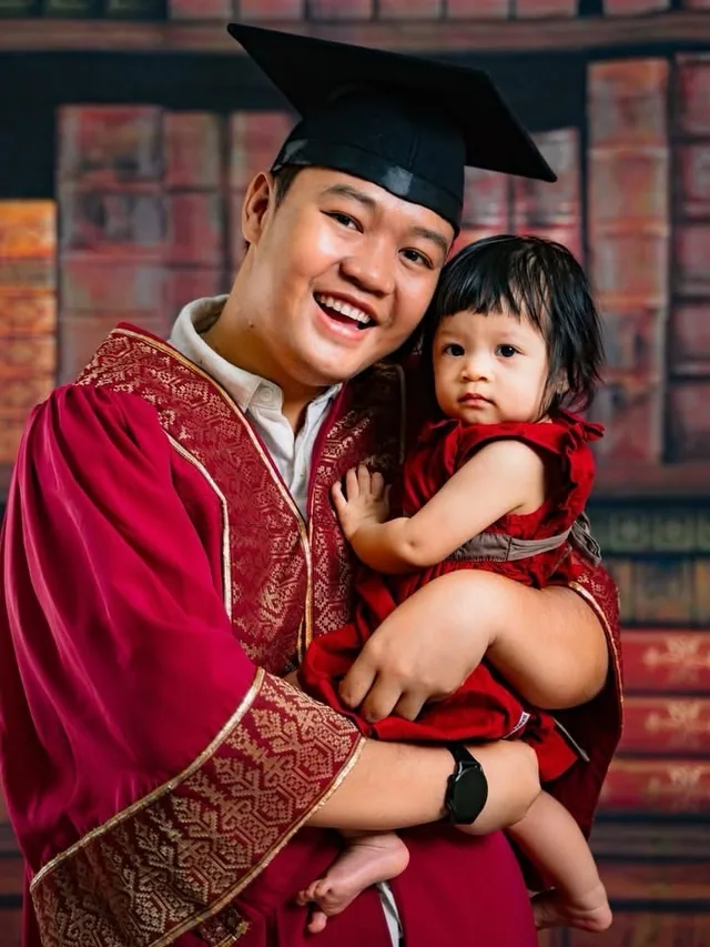 Graduate father holding his baby daughter